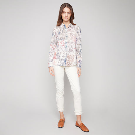 Woman wearing a floral blouse and white pants on a gray background