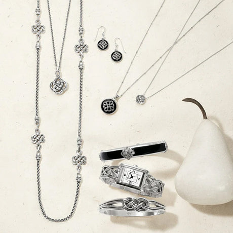Silver jewelry set including necklace, earrings, ring, and watch on a light background