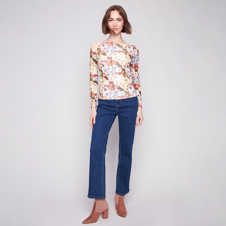 Woman wearing a floral top and blue jeans on a plain background