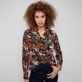 Woman wearing a patterned blouse against a plain background