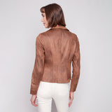 Woman wearing a brown leather jacket and white pants on a plain background