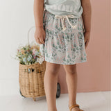 Child wearing a floral skirt with a plain background