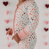 Baby in a heart-patterned onesie with a heart-themed background