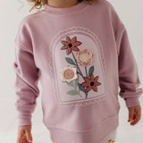 little girl in pink sweatshirt with flowers on front