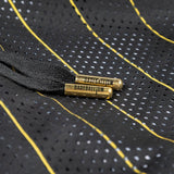 Close-up of a black mesh drawstring bag with yellow and white dotted stripes, featuring brass grommets engraved with the word 'GASTBULLISM'.