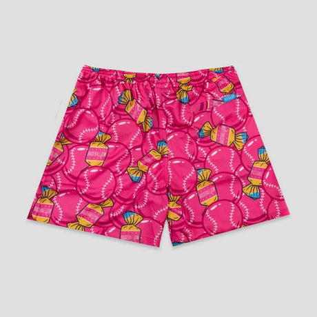 Bright pink shorts featuring an all-over pattern of baseballs and wrapped candy illustrations in yellow, blue, and white, shown flat against a light gray background.