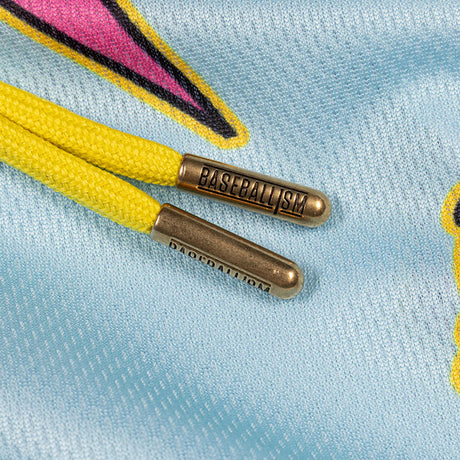 Close-up of yellow laces threaded through a light blue mesh garment, with metallic bronze lace tips engraved with the word 'BASEBALL'.