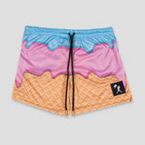 A pair of athletic shorts featuring a colorful ice cream cone design with a light blue top layer, pink middle layer, and orange waffle-textured bottom. The shorts have a black drawstring and a small black brand patch on the lower right leg.