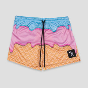 A pair of athletic shorts featuring a colorful ice cream cone design with a light blue top layer, pink middle layer, and orange waffle-textured bottom. The shorts have a black drawstring and a small black brand patch on the lower right leg.