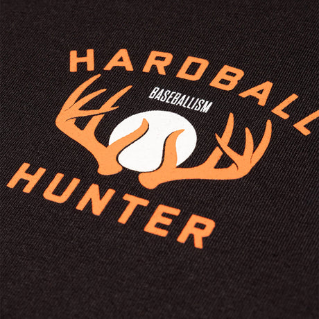 Close-up of a black fabric garment featuring a large orange and white graphic print with the words 'HARDBALL HUNTER' and 'BASEBALLISM' around a baseball and antler design.