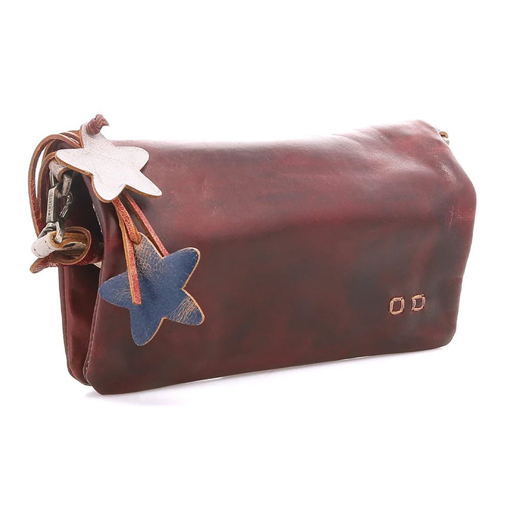A distressed reddish-brown leather shoulder bag with a star-shaped leather charm featuring a white star on the top and a blue star on the bottom, attached with brown leather cords and metal rings.