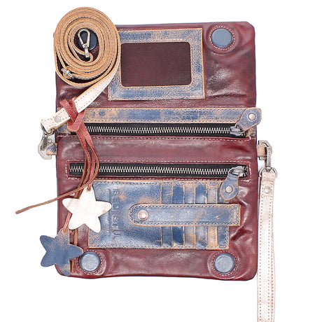 A distressed leather crossbody bag in reddish-brown with blue-toned weathered patches, multiple zip compartments, a rolled tan strap, and star-shaped charms on a plain white background.