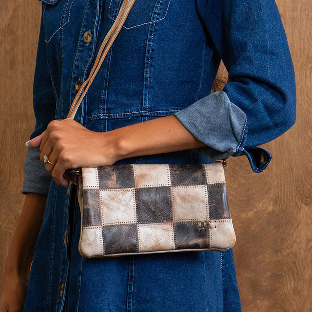 Person holding a patchwork handbag with a wooden background