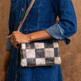 Person holding a patchwork handbag with a wooden background