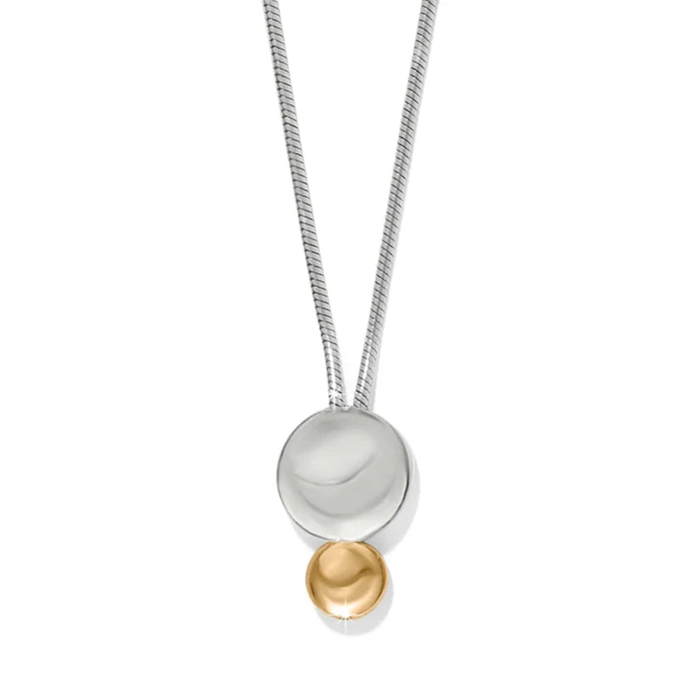 A modern two-tone pendant necklace featuring a silver snake chain, a large polished silver disc, and a small gold bead dangling below, set against a plain white background.