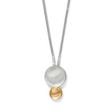 A modern two-tone pendant necklace featuring a silver snake chain, a large polished silver disc, and a small gold bead dangling below, set against a plain white background.