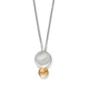 A modern two-tone pendant necklace featuring a silver snake chain, a large polished silver disc, and a small gold bead dangling below, set against a plain white background.