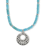 Turquoise beaded necklace with a silver pendant on a white background