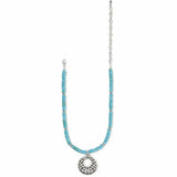 A turquoise beaded necklace with a silver-tone circular filigree pendant and matching silver chain, displayed on a clean white background.