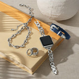 Silver chain bracelet with a black square watch face on a beige surface