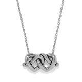 A silver necklace featuring a polished pendant made of two interlocking hearts, suspended from a delicate silver chain against a plain white background.
