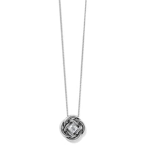 A silver necklace with a circular interwoven knot pendant featuring a small clear diamond at the center, shown against a plain white background.