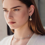 Close-up of a woman wearing a silver earring and necklace.