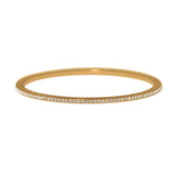 A thin gold bangle bracelet with a single row of small clear stones along the front edge, shown against a plain white background.