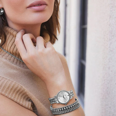 Woman wearing a silver bracelet with a circular design on her wrist.