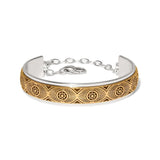 A two-tone silver and gold cuff bracelet with an engraved geometric sunburst pattern on the gold section, shown on a plain white background.