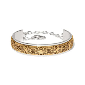 A two-tone silver and gold cuff bracelet with an engraved geometric sunburst pattern on the gold section, shown on a plain white background.