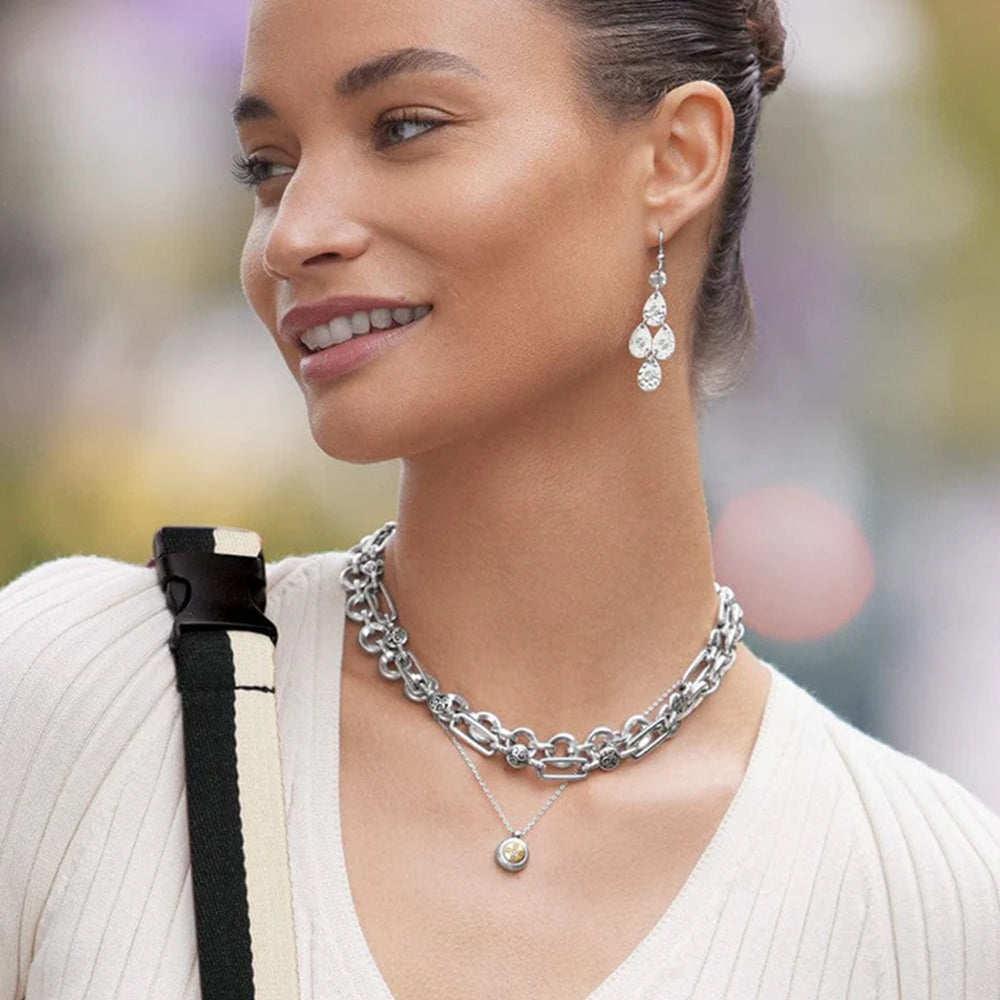 Woman wearing silver chain necklace and earrings with blurred background
