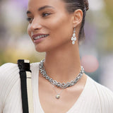 Woman wearing silver chain necklace and earrings with blurred background