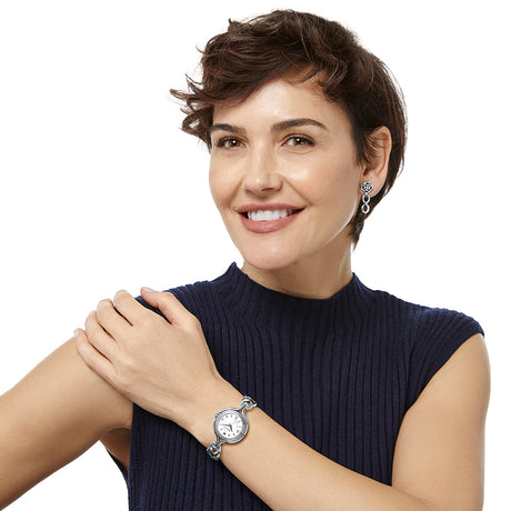 Woman wearing a watch and earrings on a white background