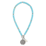 Turquoise beaded necklace with a silver and pearl charm on a white background
