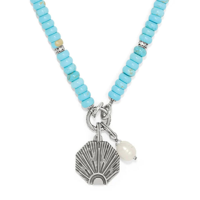 Necklace with turquoise beads and shell charm on a white background