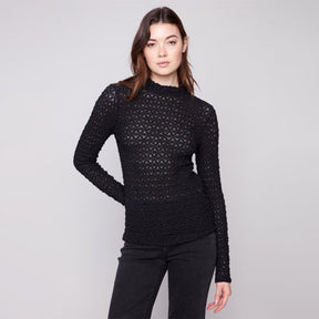 Woman wearing a black textured sweater against a plain background