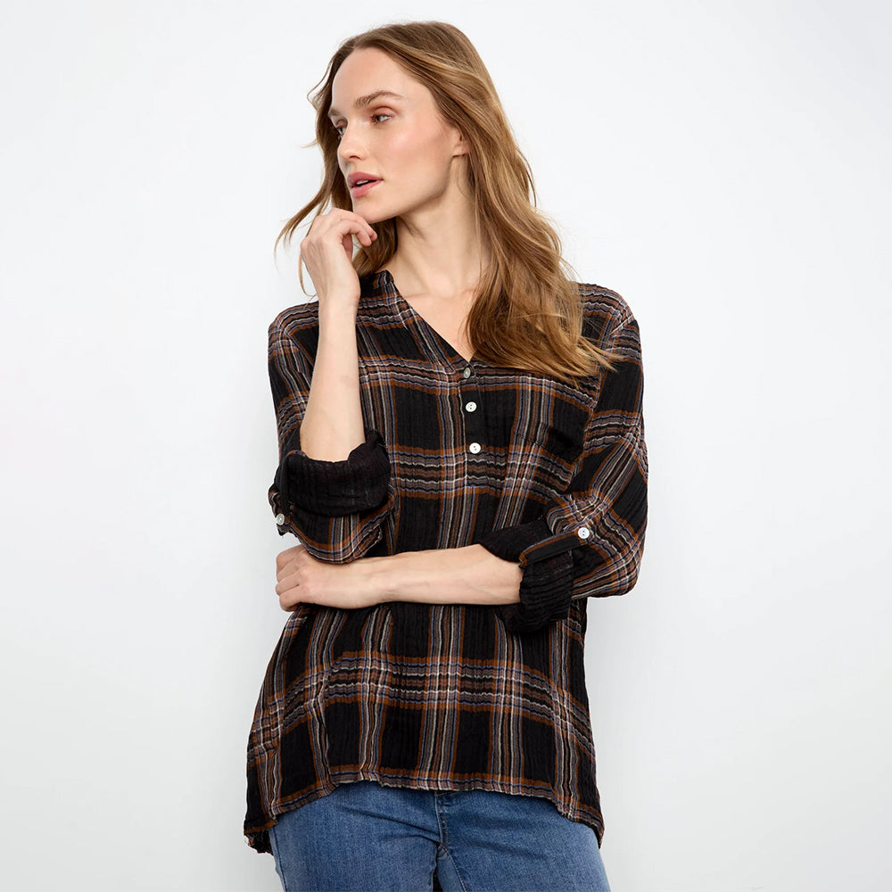 A woman modeling a black long-sleeve plaid button-up shirt with brown and orange stripes, paired with blue jeans, against a plain white studio background.