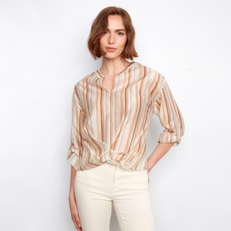 Woman wearing a striped blouse and white pants on a plain background