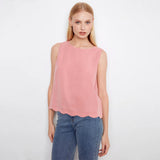 Woman wearing a pink sleeveless top and blue jeans on a white background