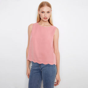 Woman wearing a pink sleeveless top and blue jeans on a white background