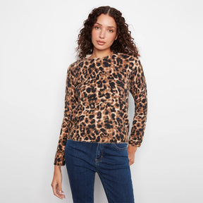 A woman modeling a long-sleeve leopard print top with dark blue jeans against a plain white background.