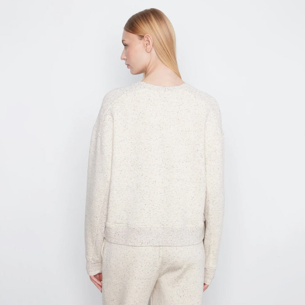 A woman shown from the back wearing a cream-colored, textured knit crewneck sweater and matching knit pants against a plain white studio background.