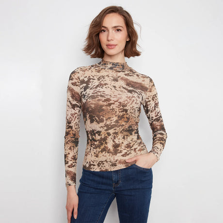 A woman modeling a fitted long-sleeve mock neck top with an abstract brown and beige pattern, paired with dark blue jeans, against a plain light gray background.