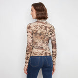 A woman shown from the back wearing a long-sleeve mock-neck top with a brown and beige abstract camouflage pattern, paired with blue jeans, against a plain white background.