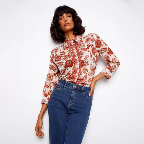 Woman wearing a floral blouse and blue jeans on a white background