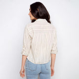 Woman wearing a striped shirt and jeans against a plain background