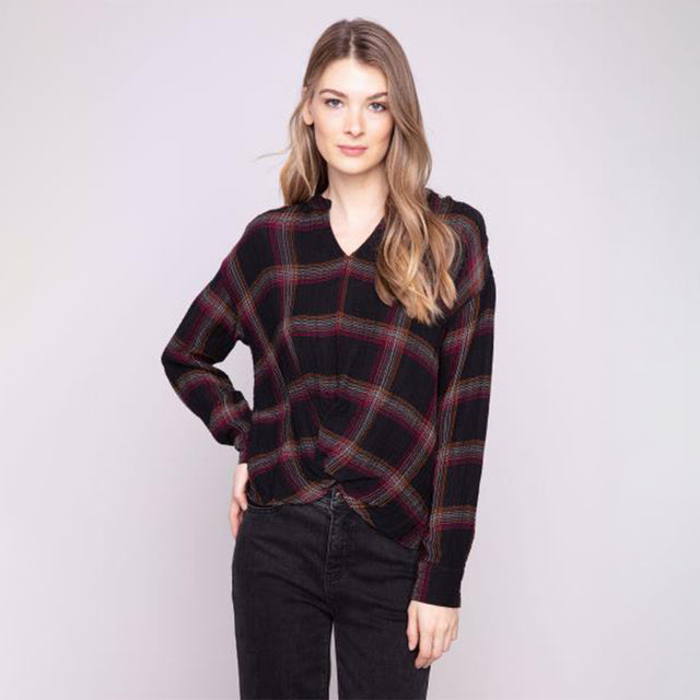 Woman wearing a plaid sweater against a plain background