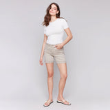 Woman wearing a white t-shirt and beige shorts on a plain background