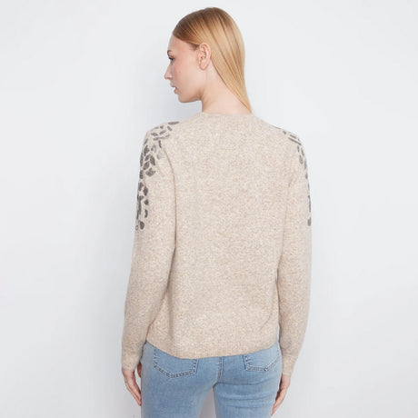 A woman shown from the back wearing a beige knit sweater with dark gray leopard print detailing on the upper sleeves, paired with light blue jeans, against a plain white background.